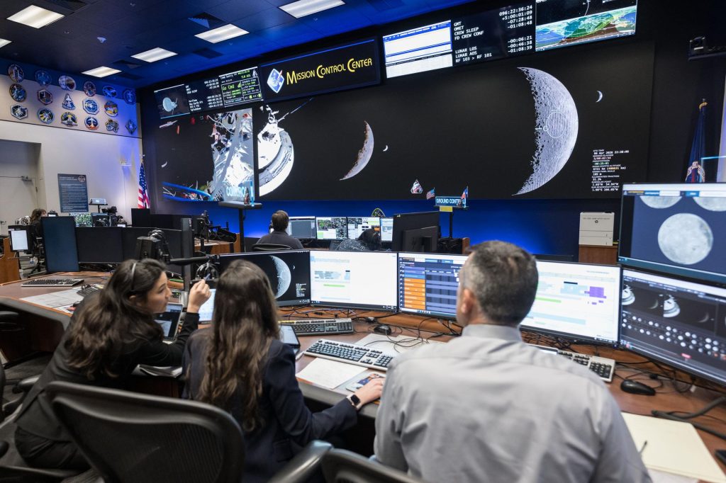 Science Officers in Mission Control jsc2026e020490 (April 6, 2026) - Pictured from left to right, Angela Garcia, Dr. Kelsey Young, and Dr. Trevor Graff, the first science officers of the Artemis program in the White Flight Control Room in the Christopher C. Kraft Jr. Mission Control Center at NASA’s Johnson Space Center. Seen here about ten minutes before Earthset during Artemis II, these science officers are seen monitoring mission data in real-time from the Science console. They support flight controllers by analyzing scientific measurements and system performance. Their work helps ensure mission objectives are achieved safely and efficiently. Credit: NASA